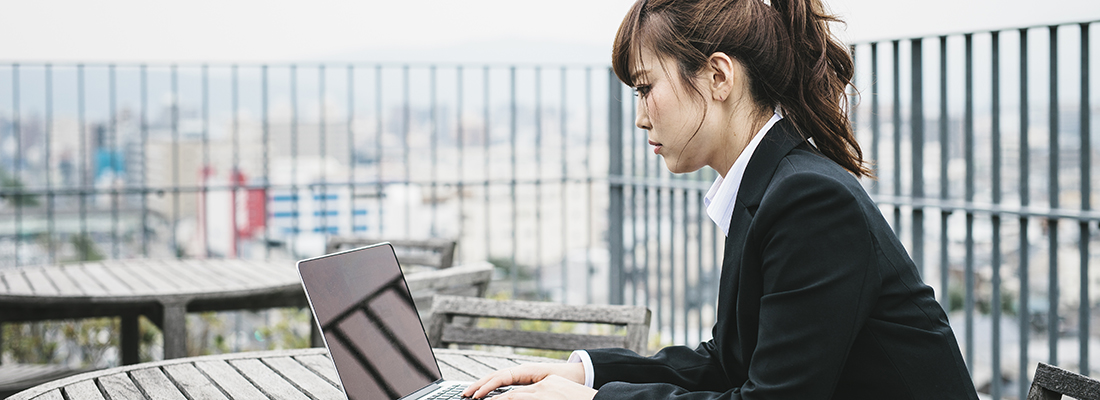 Eine Frau in Kyoto, Japan, arbeitet draussen im Freien an einem Laptop